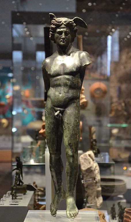 A gleaming black statuette of Mercury. Wings sprout out of His feathered hair, which is blown back by the wind. His feet fall limp, as if He is floating off the ground. Both of His arms are missing below the shoulder. His muscular physique slightly twists, in a contrapposto pose. He looks down with a serious expression on His face.